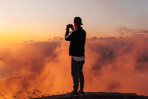 Free Man in Black Shirt and Pants Standing on Rock during Sunset Stock Photo