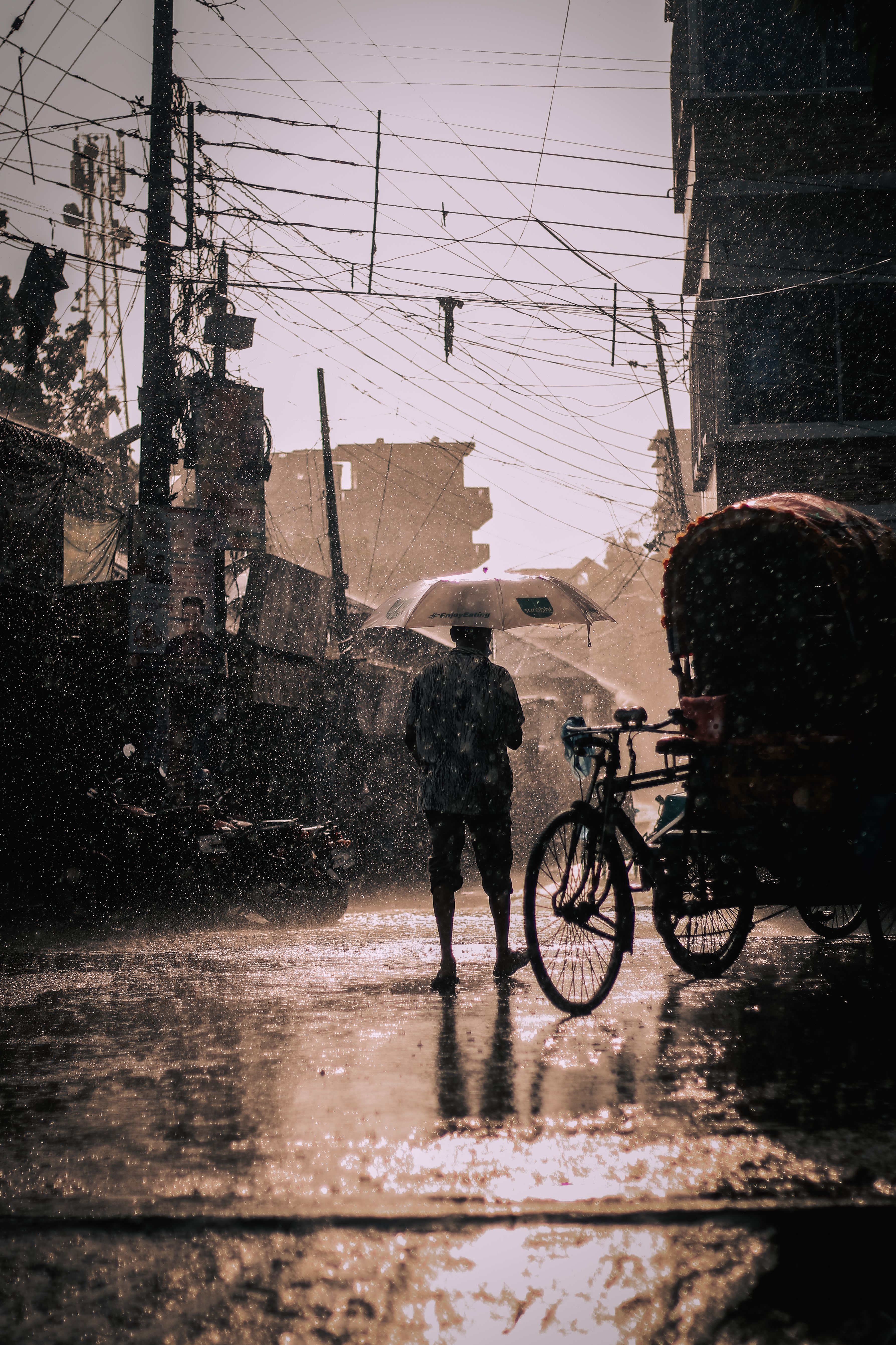 一个撑着伞的人影穿过雨中的街道，营造出忧郁的城市氛围