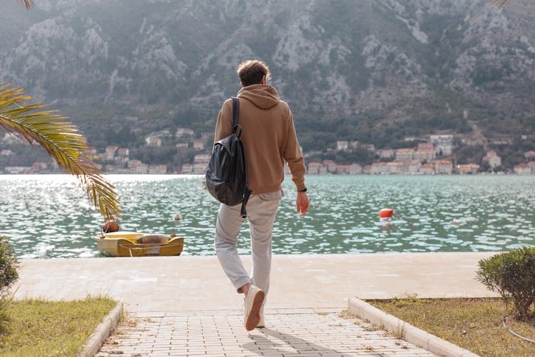 Man In Brown Hoodie Walking Near Water