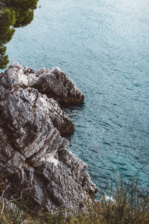 Free High angle view of rocky cliffs above a shimmering turquoise sea on a sunny day. Stock Photo
