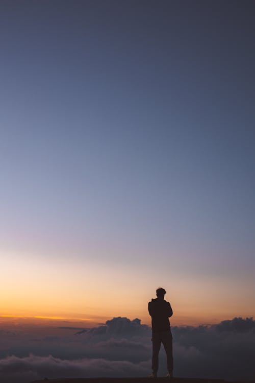 Silhouette of Man Standing on Hill during Sunset
