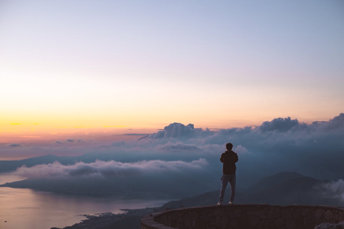 Man Standing on Rock Formation during Sunset