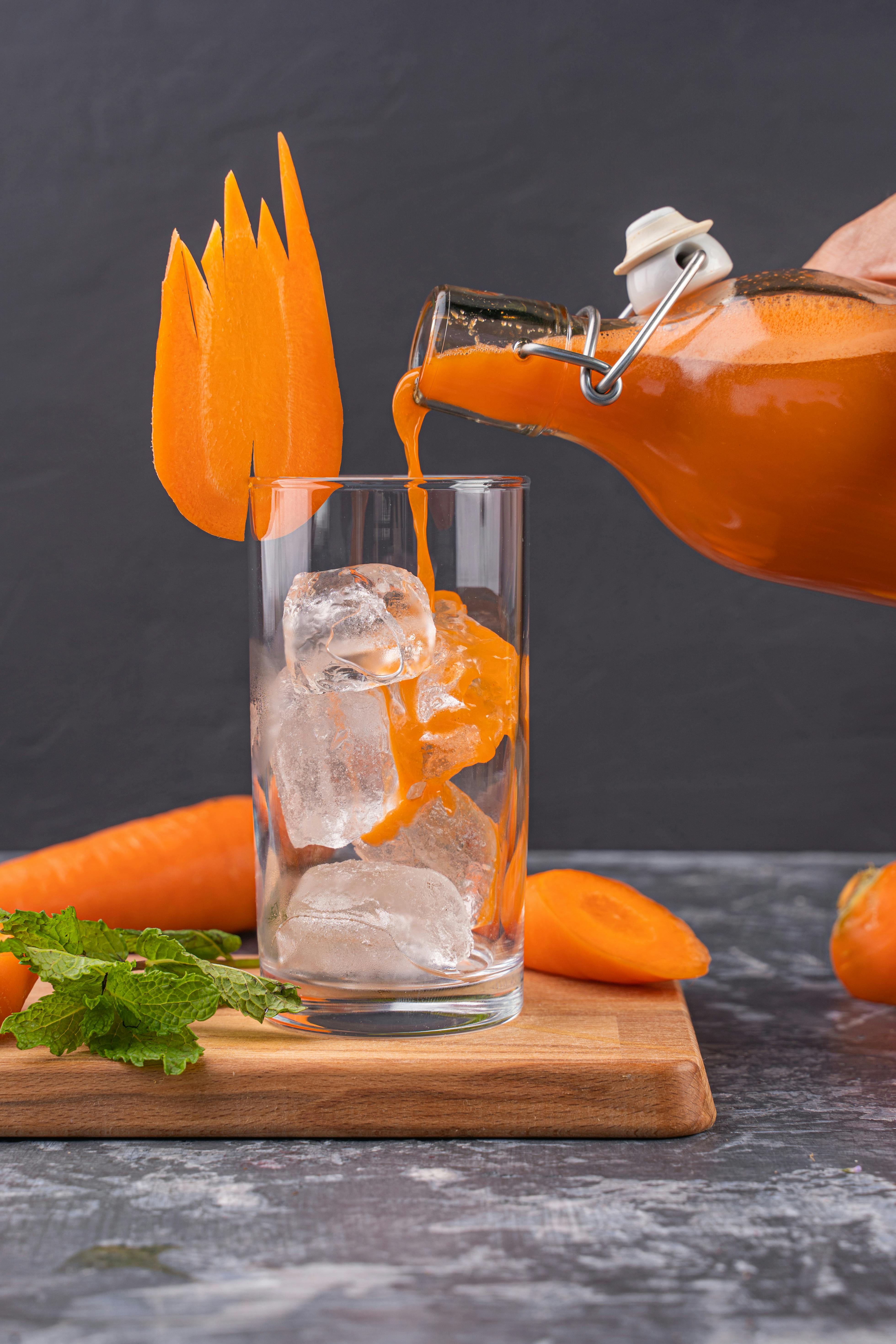 Free A Person Pouring Carrot Juice in the Glass Stock Photo