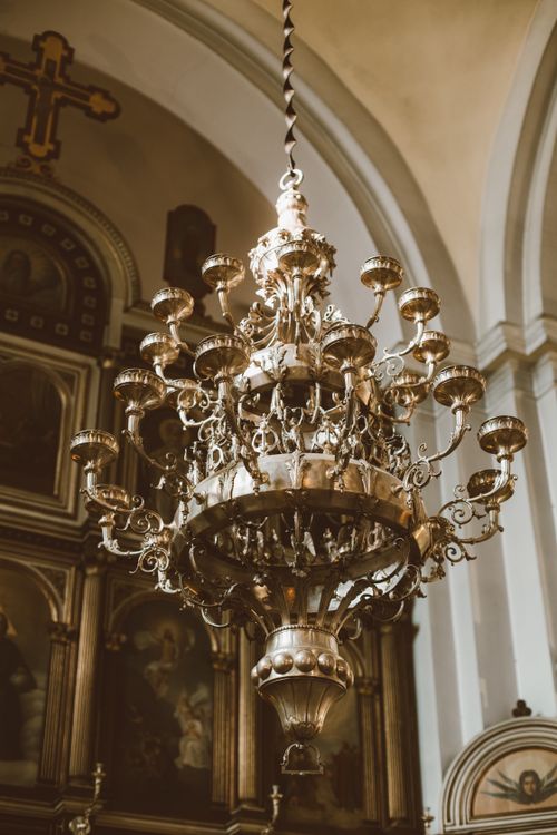 Free Majestic brass chandelier with intricate design hanging in an ornate church interior. Stock Photo