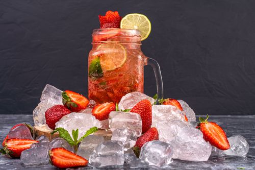 Free A vibrant strawberry and lime iced drink surrounded by fresh strawberries and ice cubes. Stock Photo