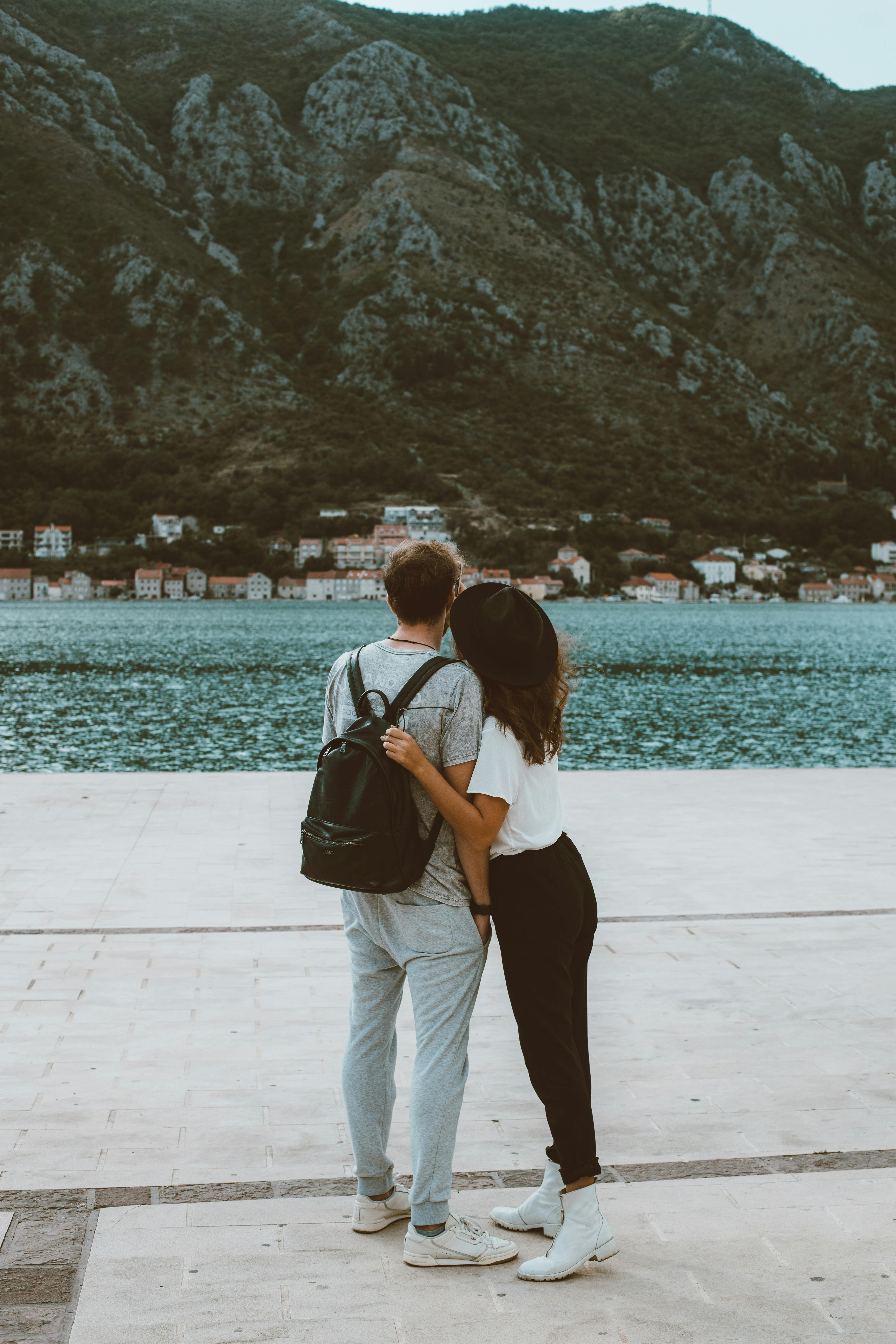 一对夫妇在湖边拥抱，以山为背景，营造出浪漫的场景