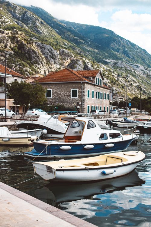 Free A picturesque harbor with boats docked against a stunning mountainous backdrop. Stock Photo