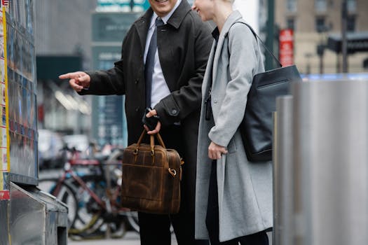 Two business professionals in formal wear ordering food from a street vendor in the city.