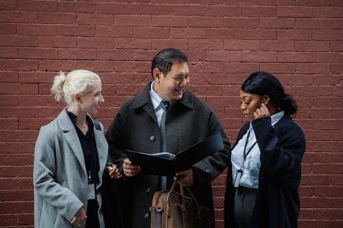 Free Positive diverse business people examining documents on street Stock Photo