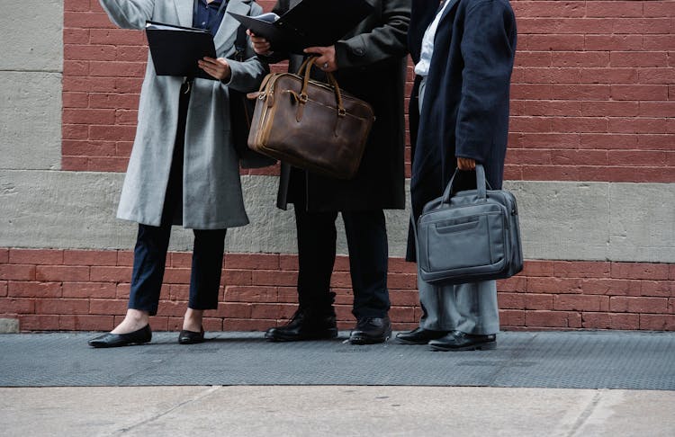 Anonymous People In Formal Clothes Reading Documents On Street