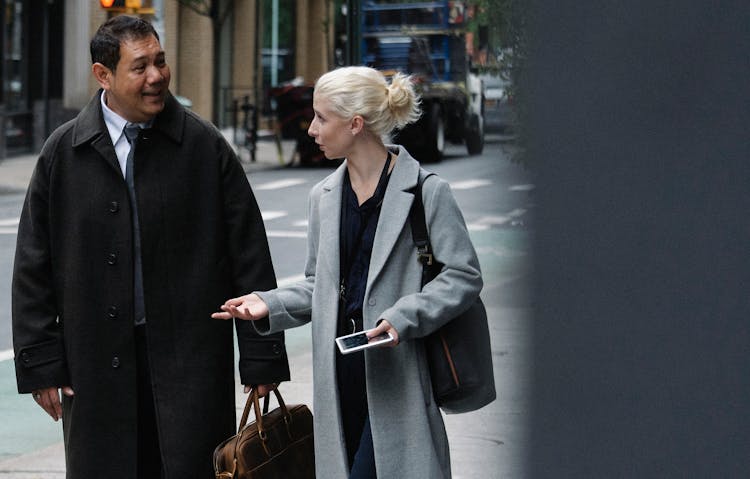 Elegant Woman With Smartphone Chatting With Ethnic Male Coworker On Street