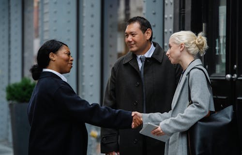 Positive multiracial coworkers doing handshake on street after business meeting