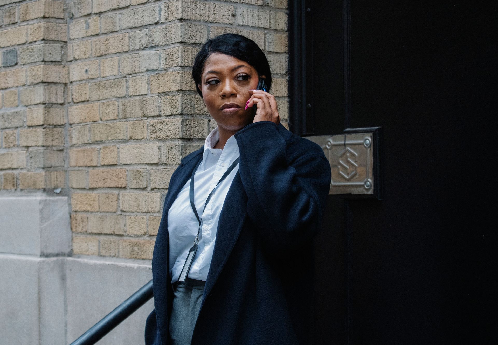 Confident adult African American female entrepreneur in formal clothes and coat standing on street and talking on mobile phone