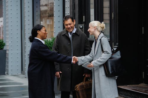 Cheerful diverse colleagues smiling and shaking hands after leaving office