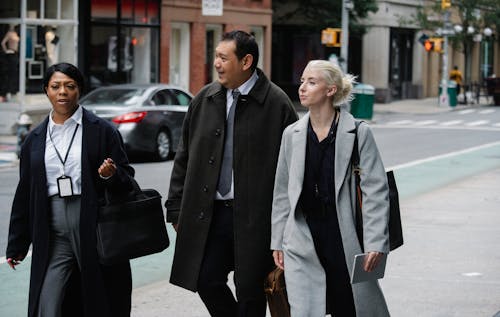 Group of confident multiracial coworkers in elegant outfits walking together on city street during business meeting in downtown