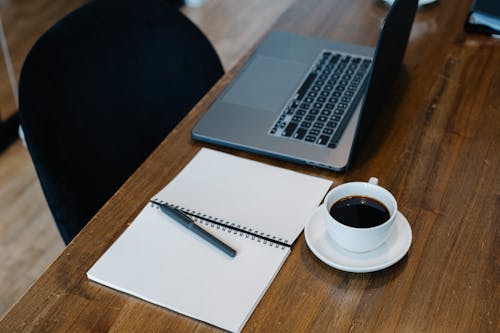 Free Workplace with laptop and notepad placed near coffee cup Stock Photo