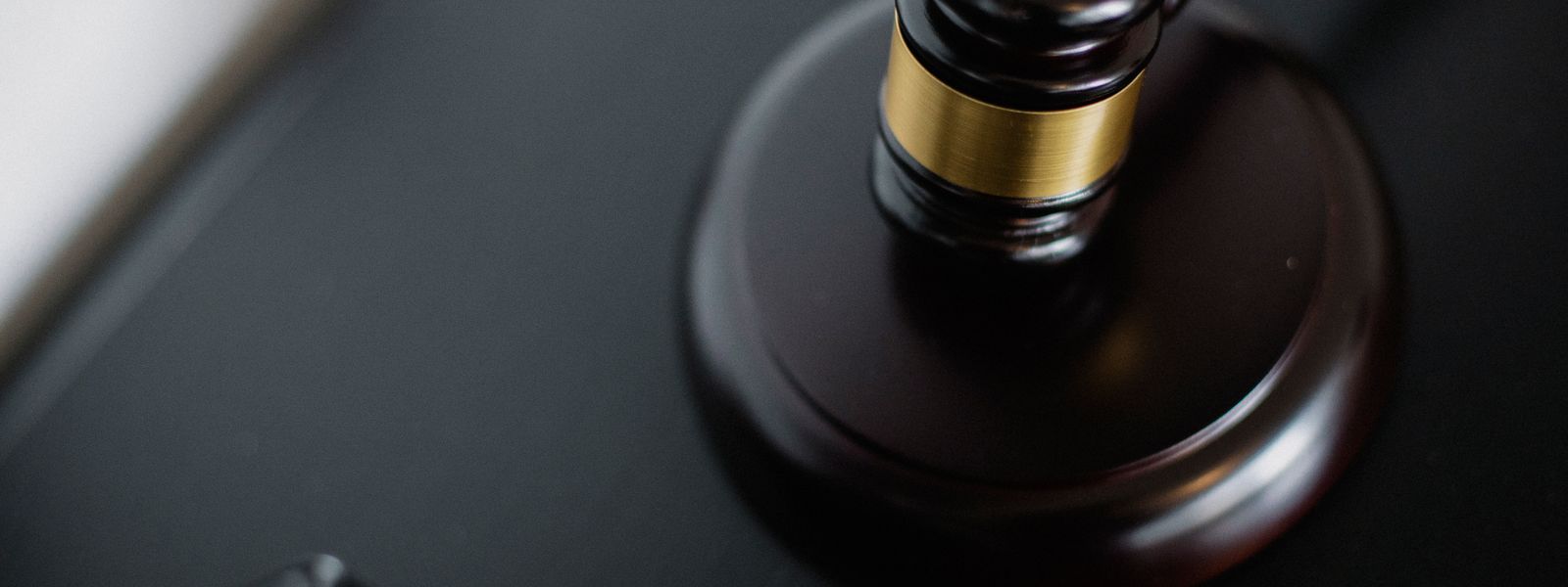 From above of wooden gavel on round surface near folders on table in courtroom