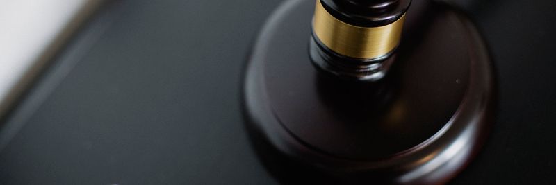 From above of wooden gavel on round surface near folders on table in courtroom