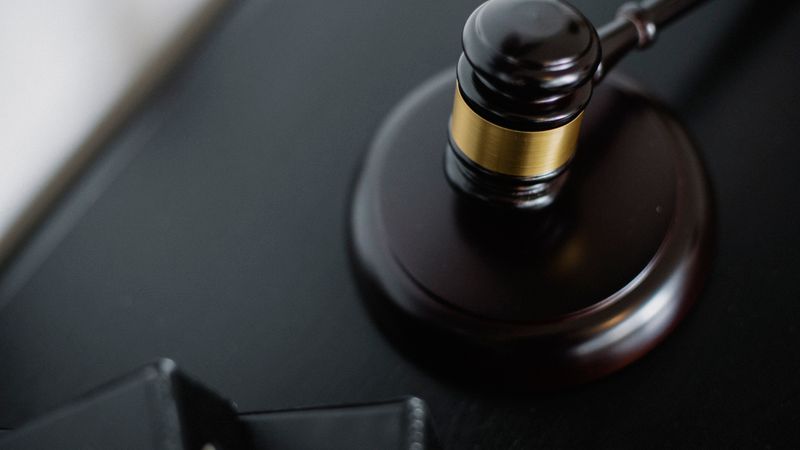 From above of wooden gavel on round surface near folders on table in courtroom