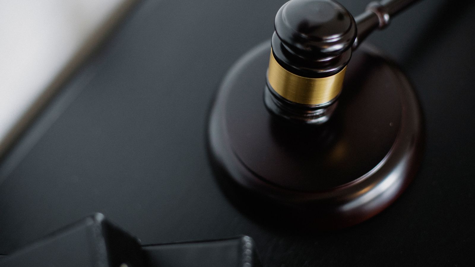 From above of wooden gavel on round surface near folders on table in courtroom