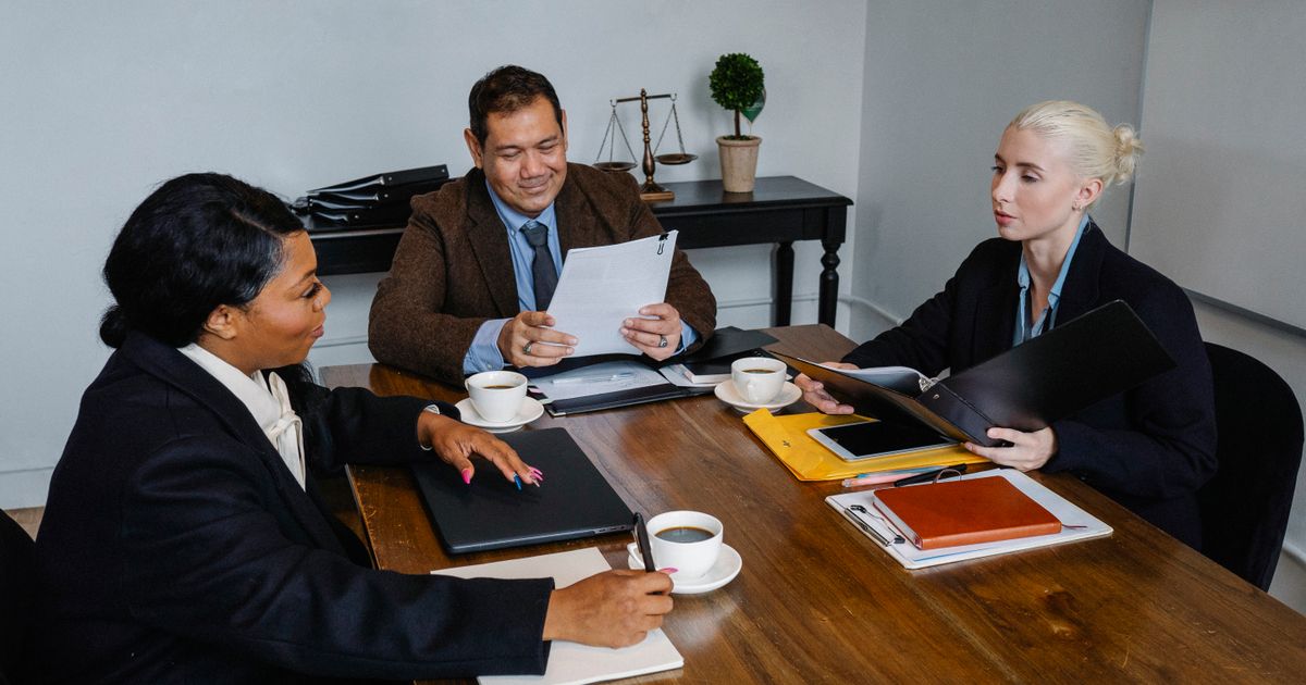 Group of diverse coworkers in formal suits discussing business issues during meeting in office