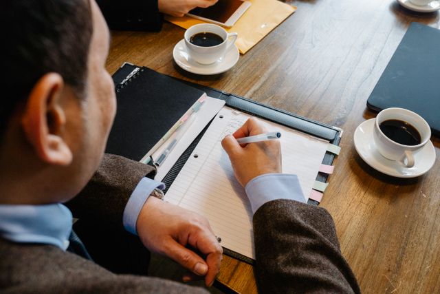 Cadre prenant des notes à une table de travail pendant un entretien de coaching