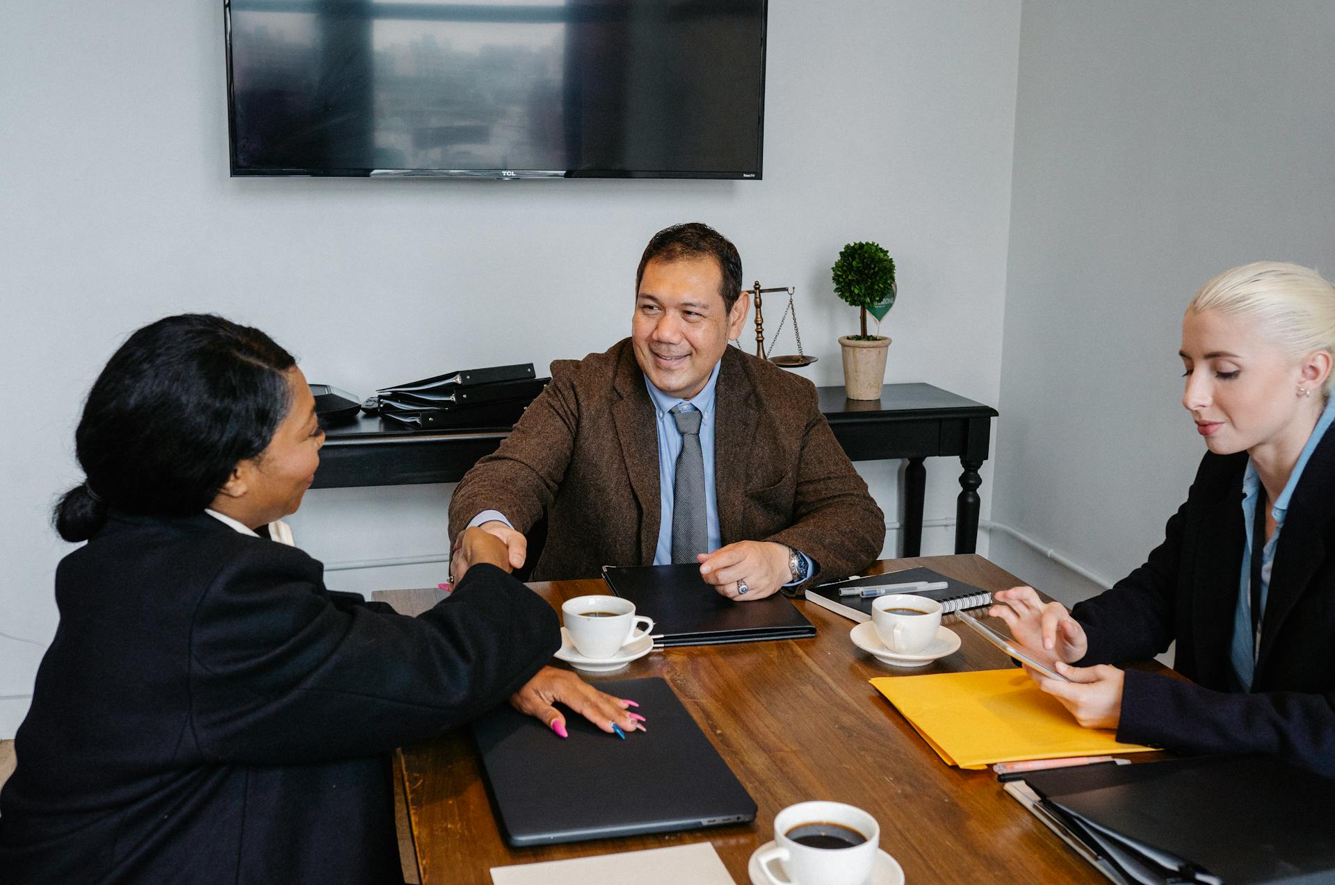 Group of colleagues closing deal and shaking hands after successful business meeting in office