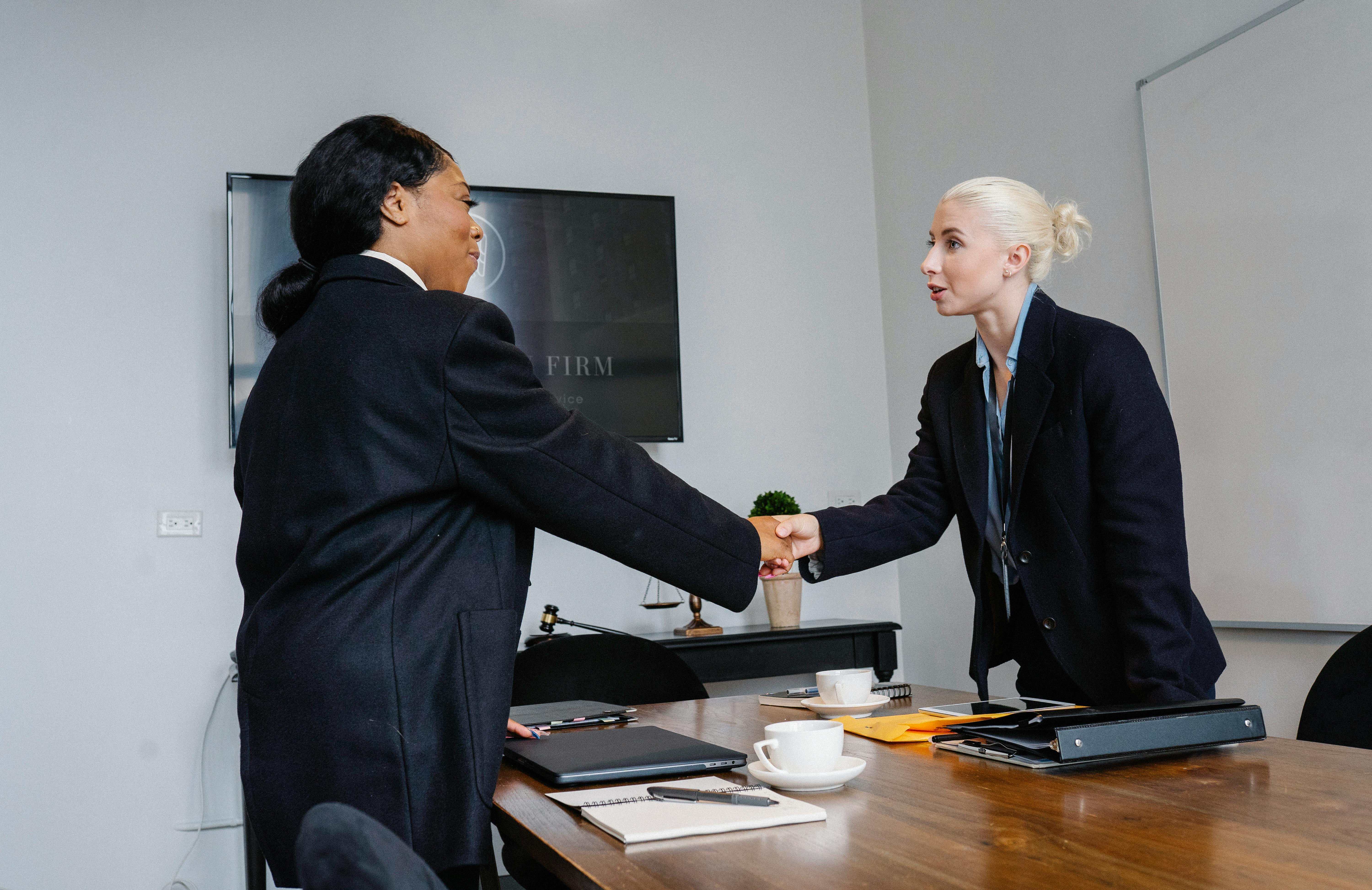 cheerful colleagues shaking hands in office