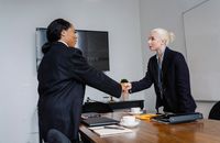 两名女商人在公司办公室里握手，象征着成功与合作