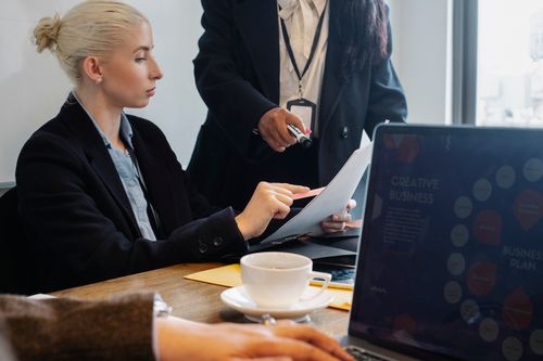 Free Group of young coworkers in formal wear gathering at table and discussing details of business plan in modern workspace Stock Photo