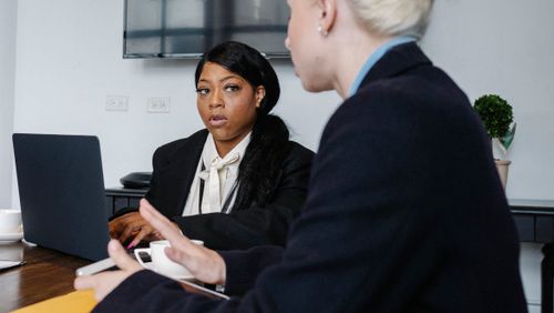 Free Serious diverse coworkers in formal wear gathering at table with gadgets and discussing business strategy while working in office Stock Photo