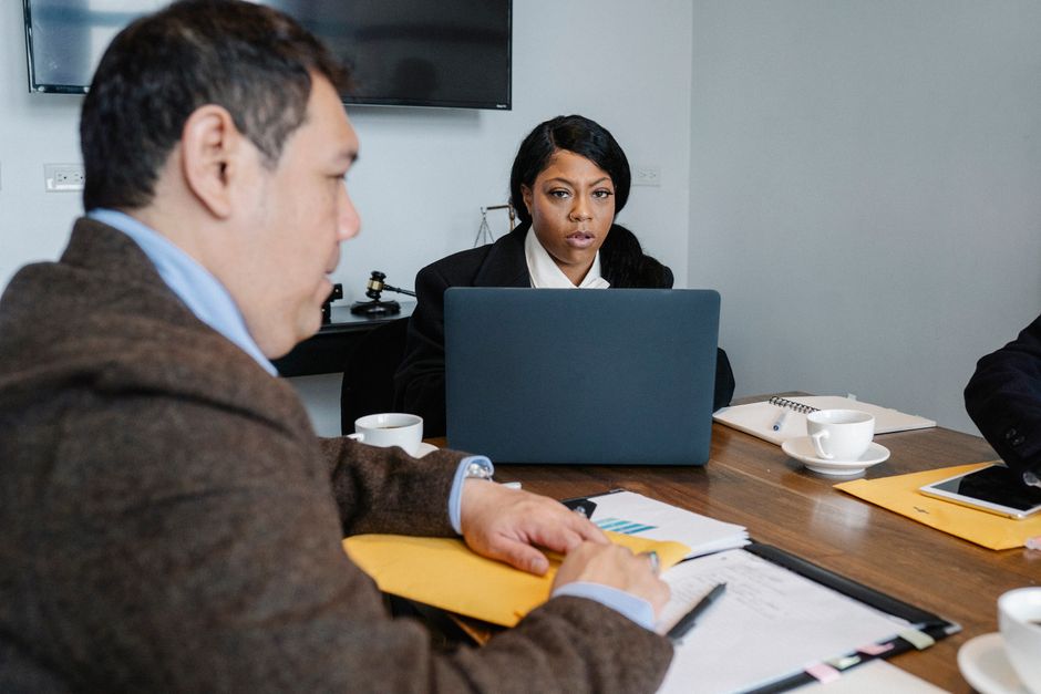 Reunión profesional con un equipo diverso discutiendo la estrategia del proyecto alrededor de una mesa con portátiles.