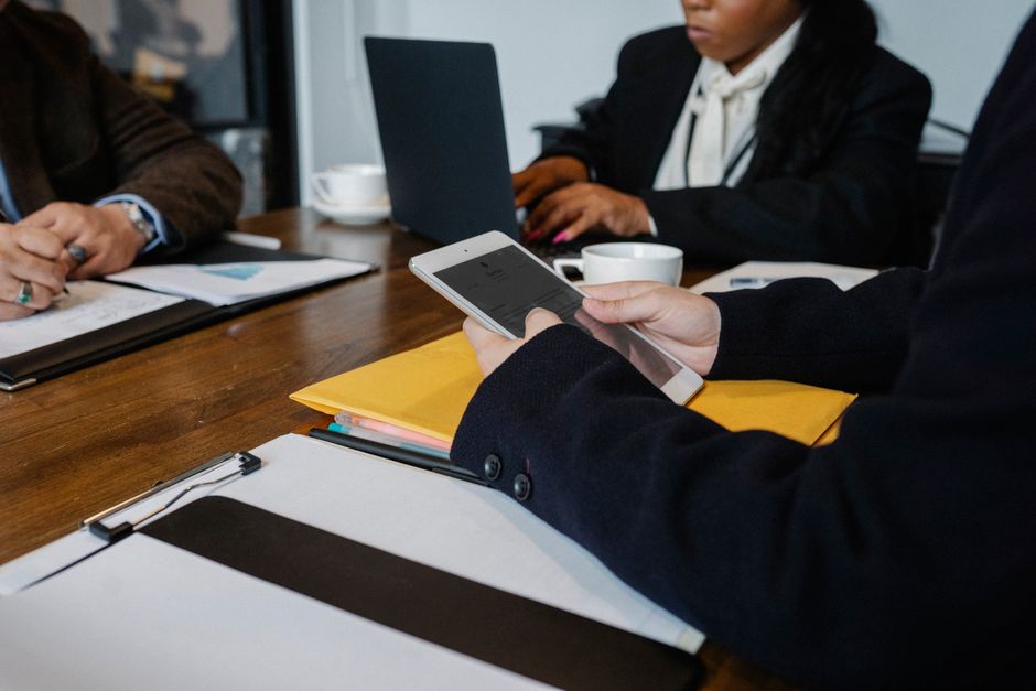 Equipo de negocios diverso colaborando con tecnología en una mesa en interiores.