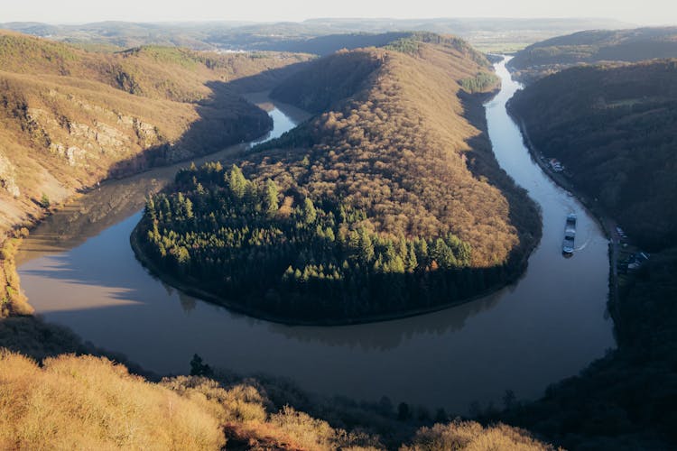 Boat Floating On Winding River In Hilly Terrain