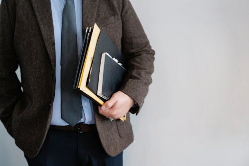 Crop unrecognizable office worker standing with papers in hand