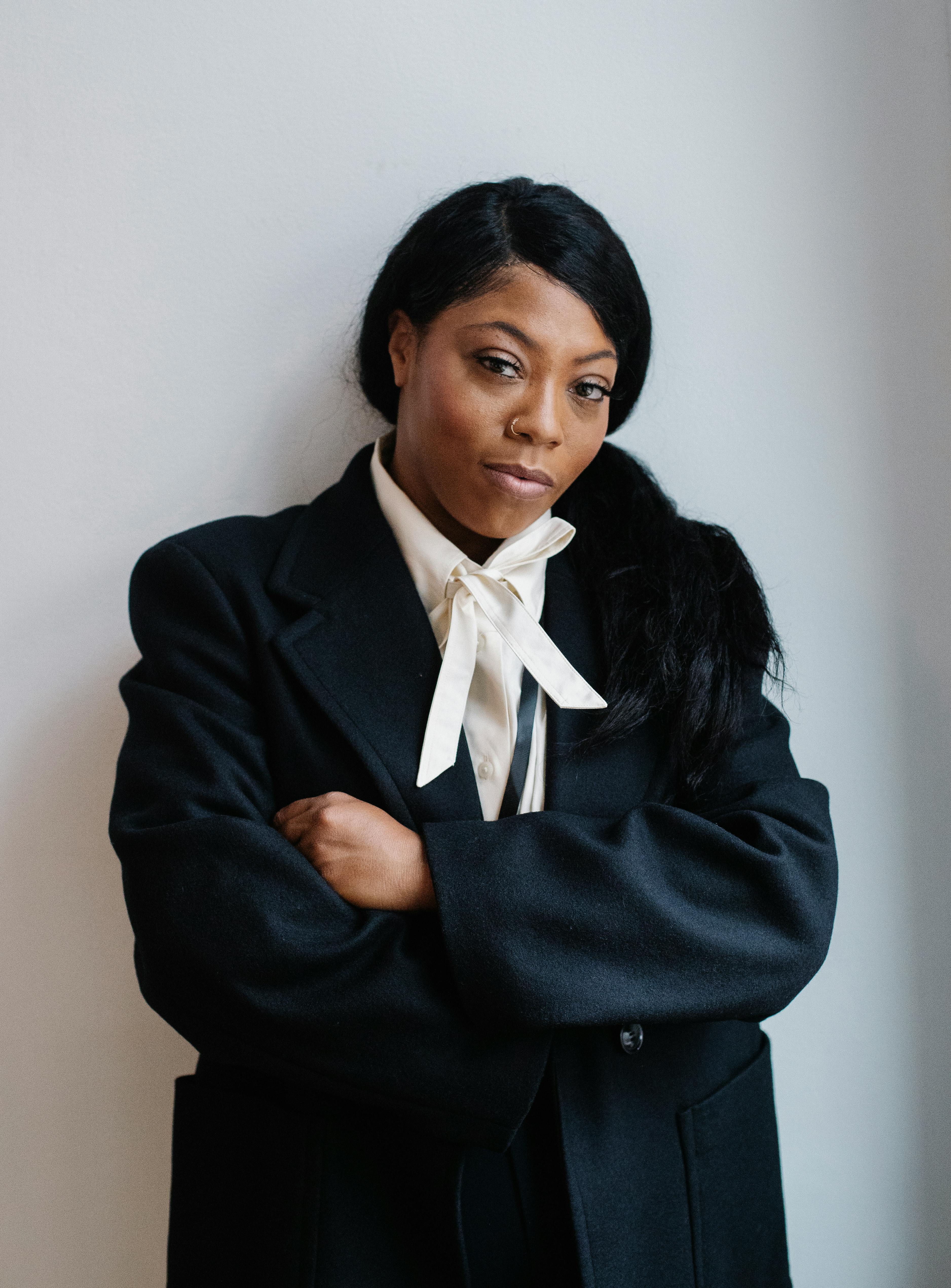 content black woman in formal clothes standing with arms crossed