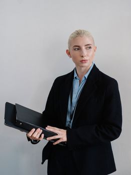 一位自信的女商人拿着文件夹，在公司里若有所思地看着旁边