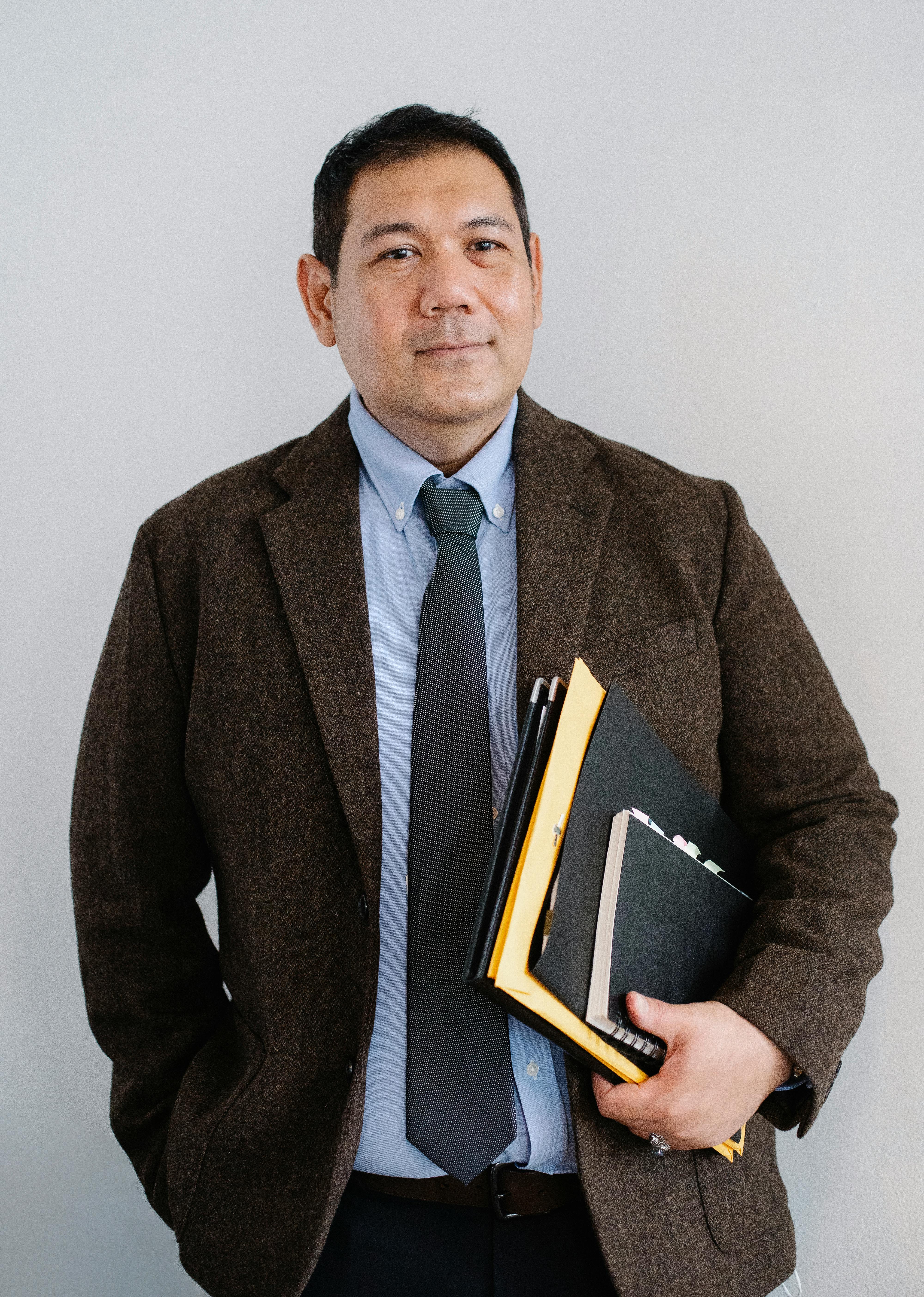 glad asian businessman standing with documents in hand in office