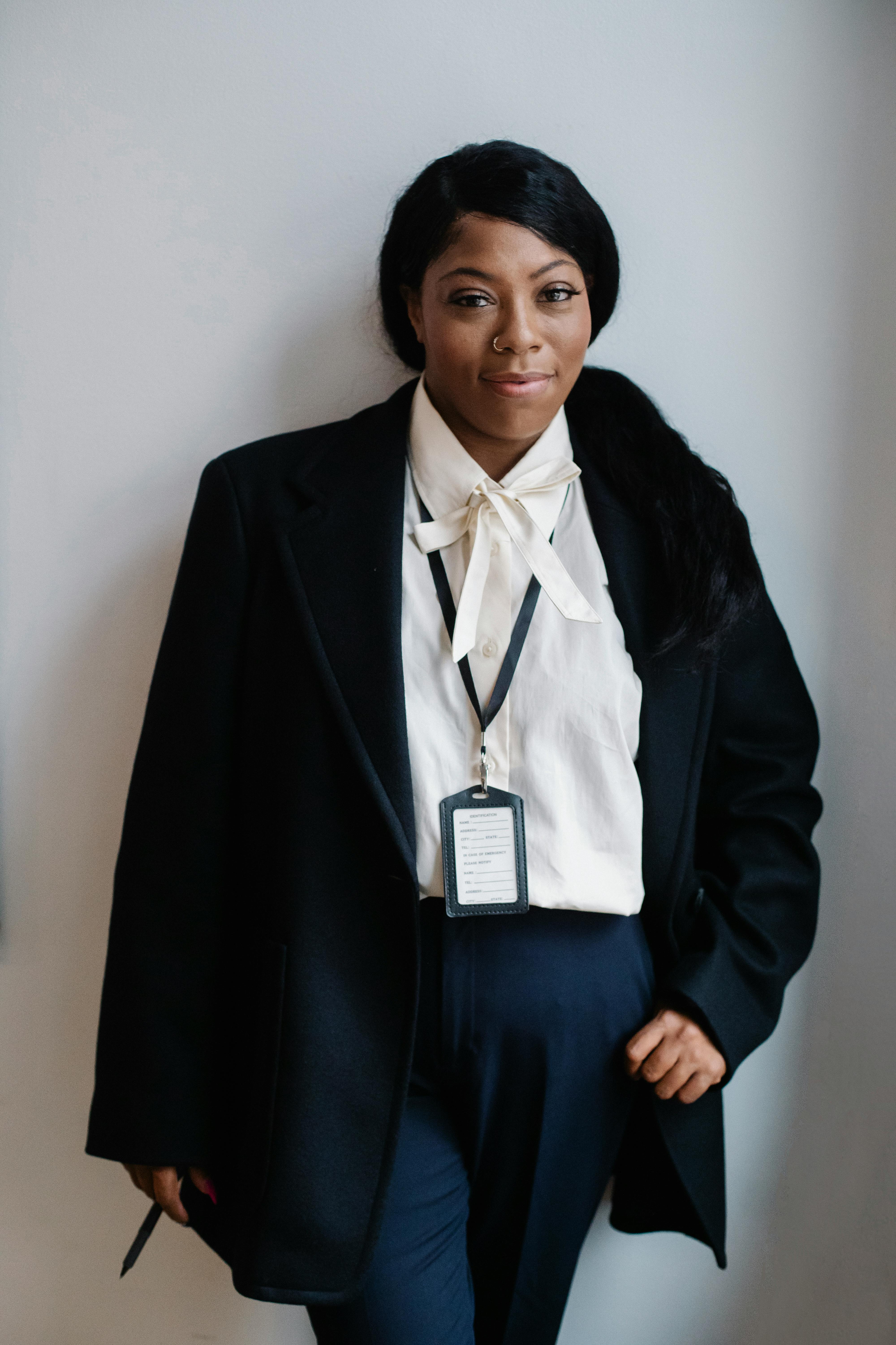 positive black woman in formal suit standing against white wall