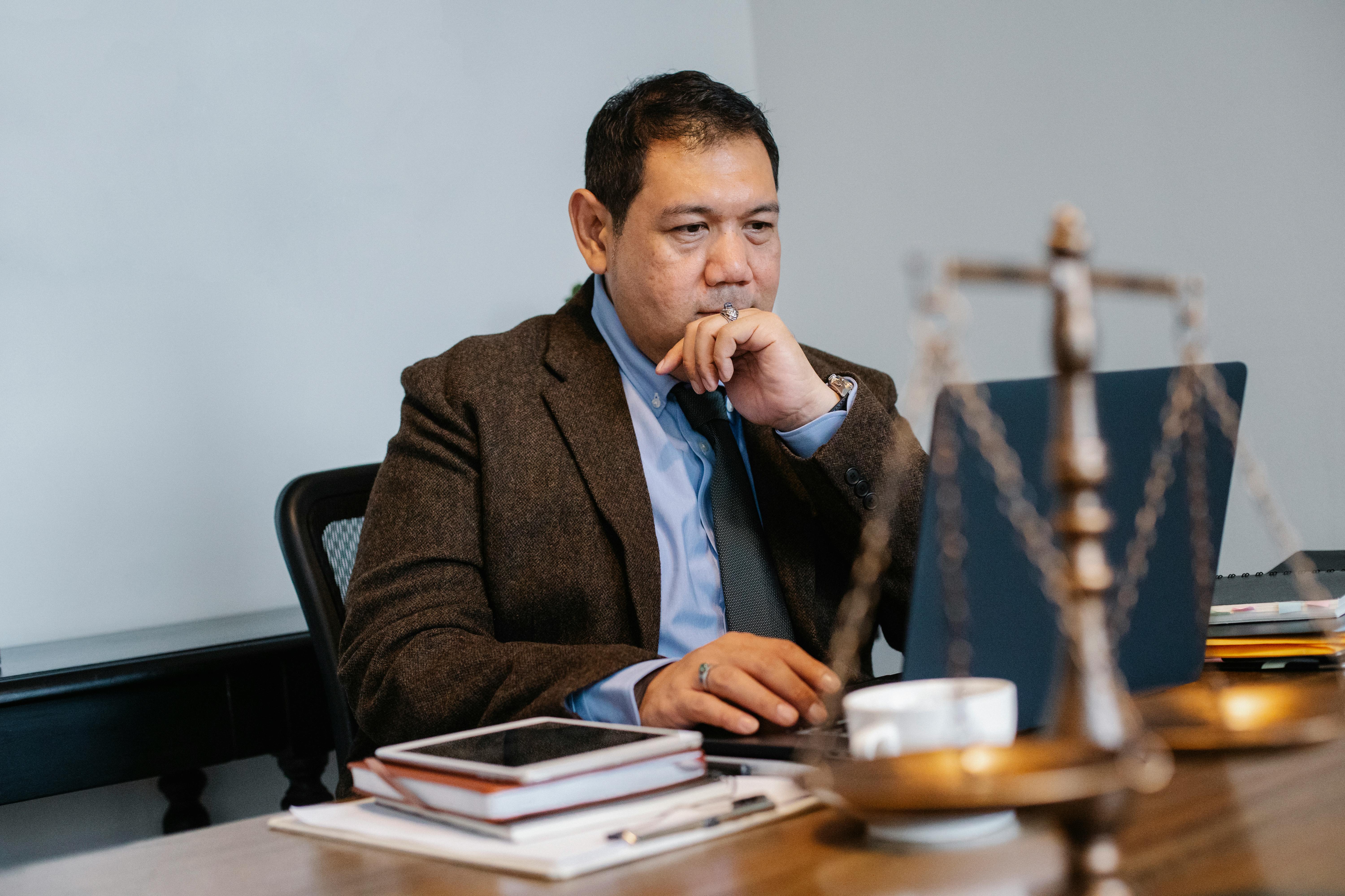 contemplative asian lawyer working on laptop in law firm