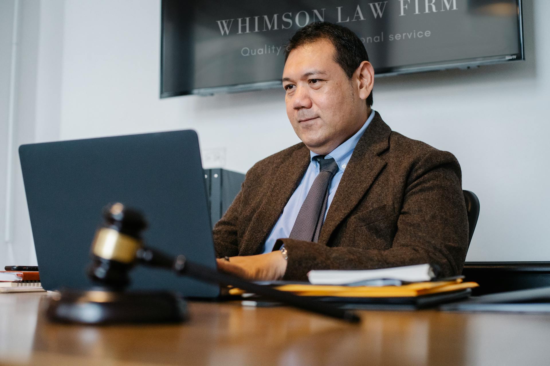 Positive Asian lawyer using laptop in modern office