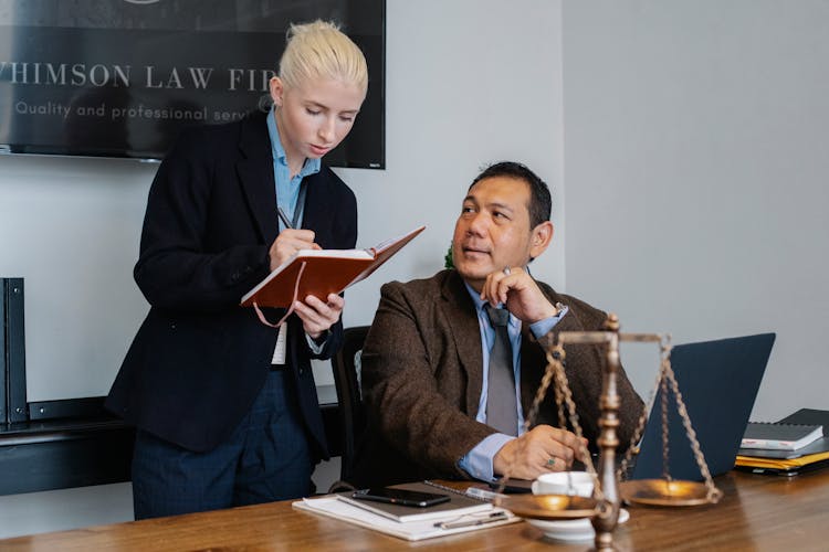 Diverse Serious Law Office Colleagues Taking Notes And Using Laptop