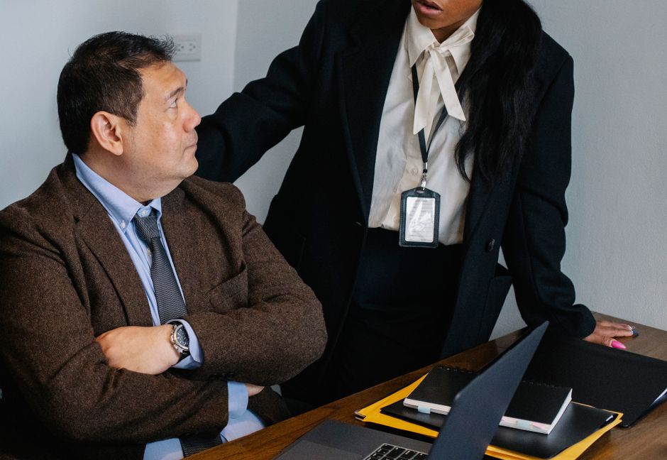 Dos profesionales de negocios involucrados en una discusión seria en la oficina con un portátil.