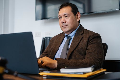 Fokussierter Ethnischer Geschäftsmann, Der Netbook Benutzt, Während Er Im Büro Arbeitet