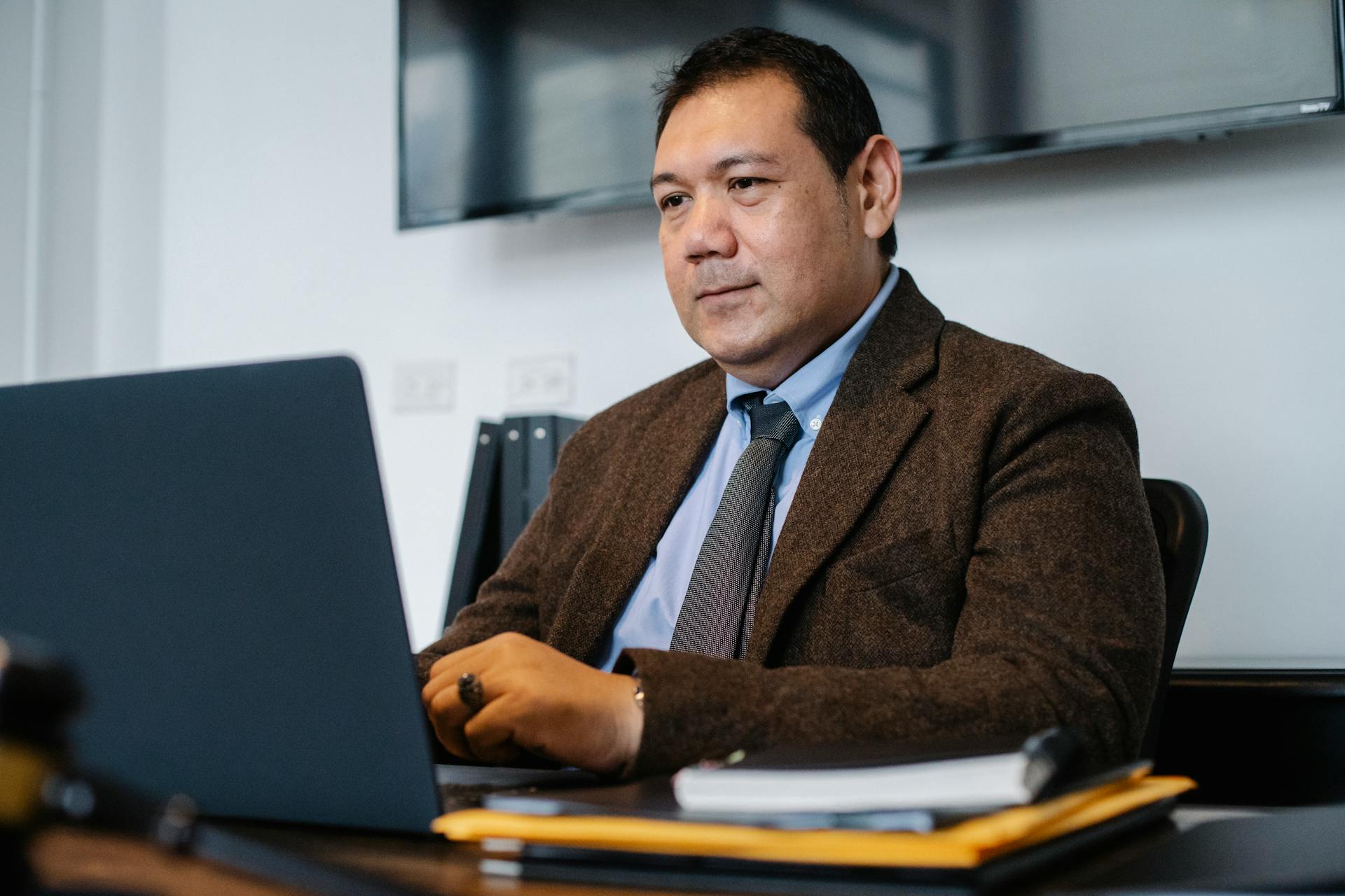 A confident businessman in a suit working on his laptop in the office.