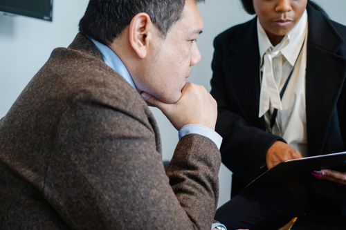 Free Crop concentrated adult multiethnic colleagues in formal suits analyzing documents while working together in modern office Stock Photo