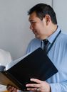 Smart mature male manager holding documents folder and looking away