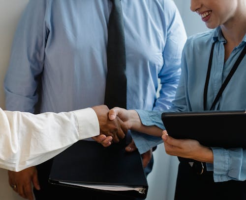 Anonymous colleagues shaking hands and smiling after meeting