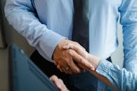 High angle of crop unrecognizable male and female business partners in formal clothes shaking hands after successful deal