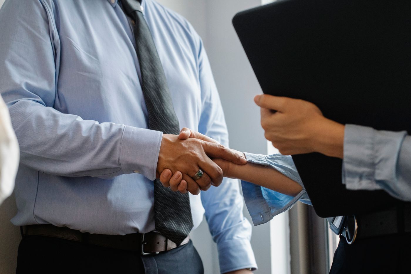 Sales and marketing professionals shaking hands with a colleague or client in a modern office after a commercial conversation